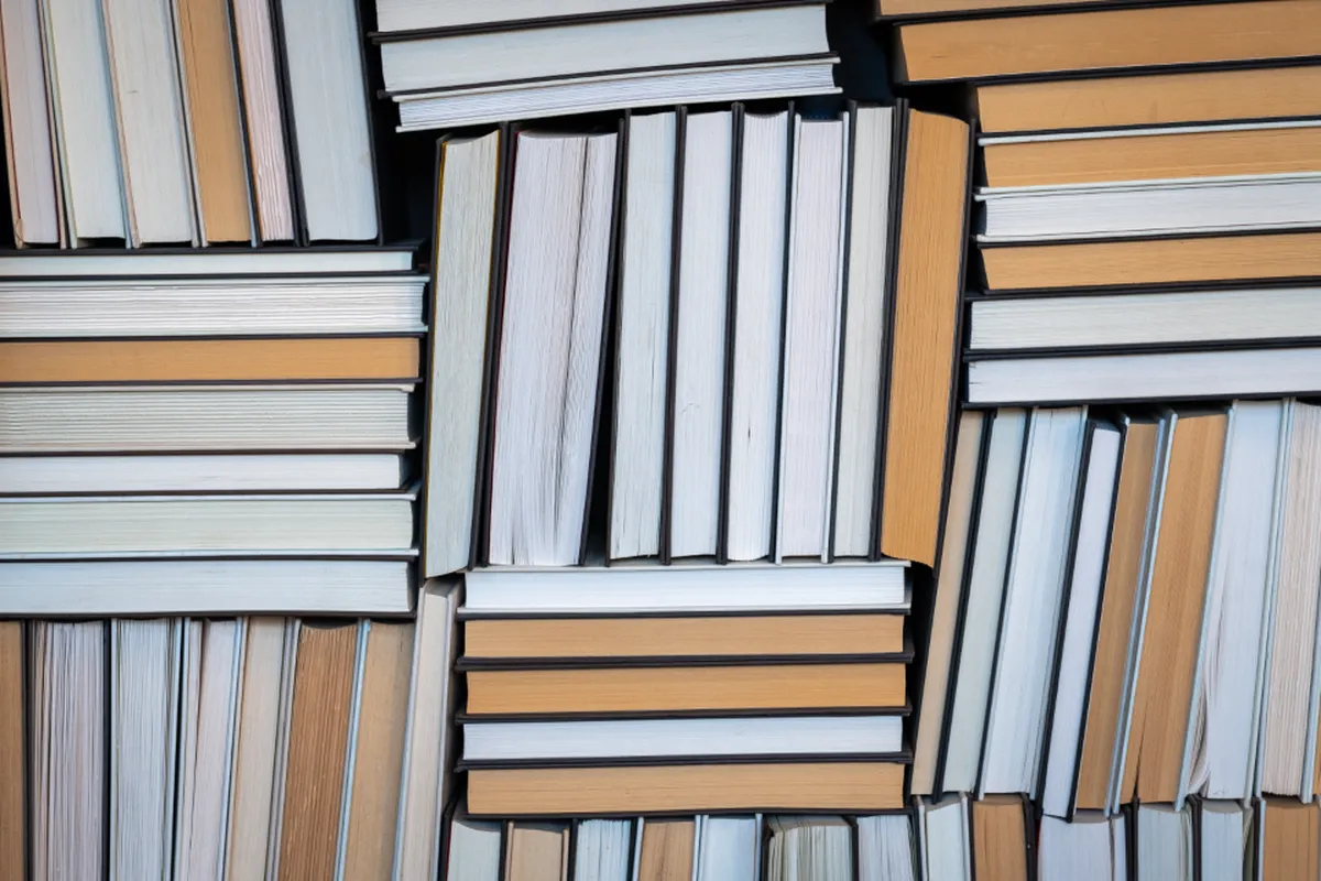 Livros empilhados, lado a lado, formando um mosaico de lombadas e páginas